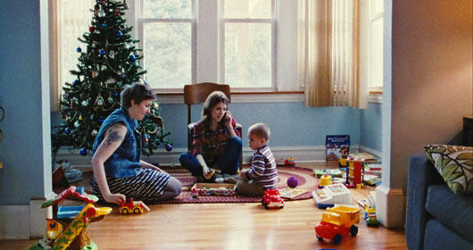 A family sits by a large christmas tree on Christmas morning