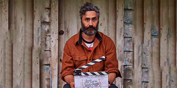 Bearded man holding a director's clapboard.