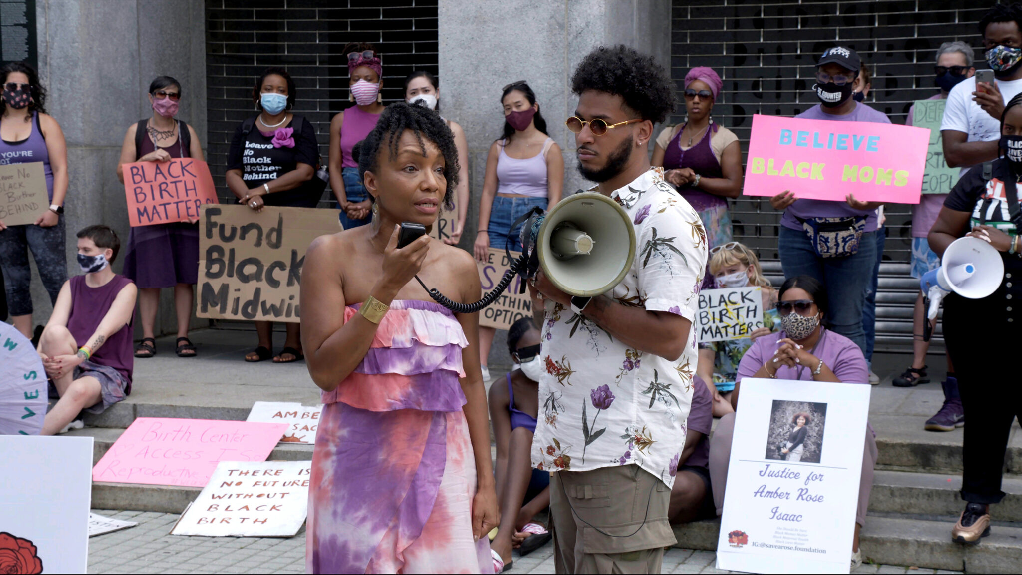 Two people standing with a megaphone outside of a protest