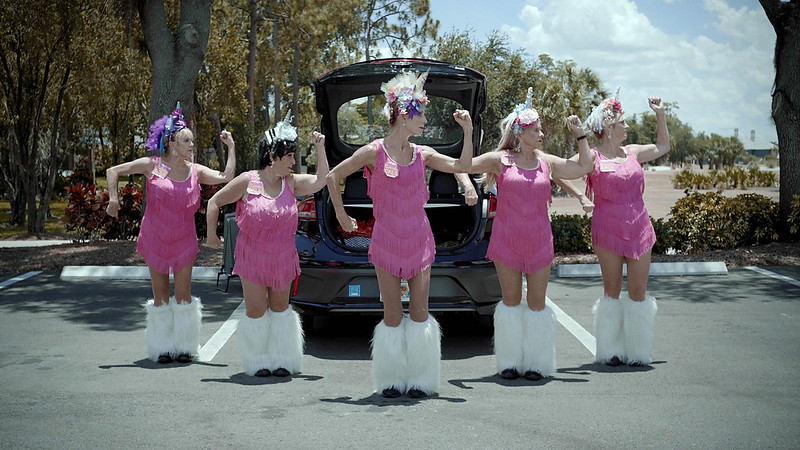 A group of women in pink and white outfits dancing together outside