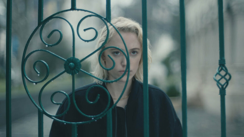 Blond woman stands behind a gate