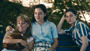 Three young friends relax on a park bench.