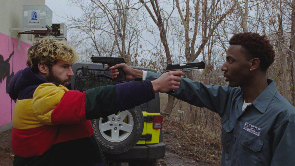 Two men point guns at each other's head.