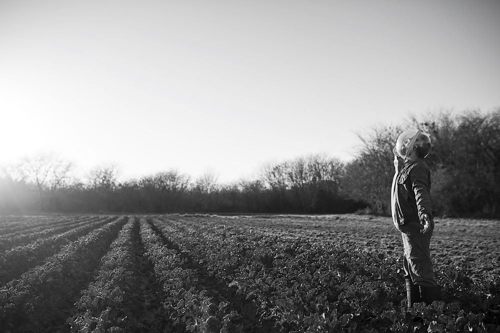 A man in bubble headgear stands in a field.