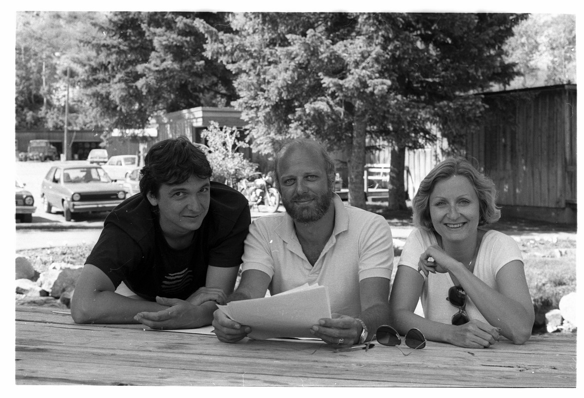 Three people sit at a picnic table.