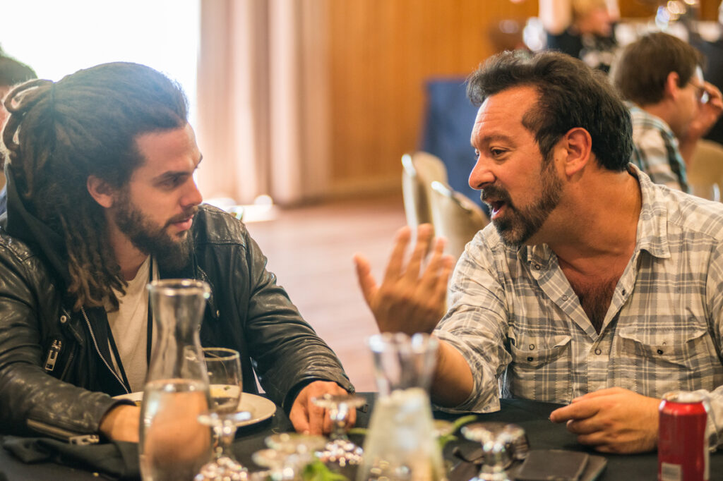 Two men hold a conversation at a dining table