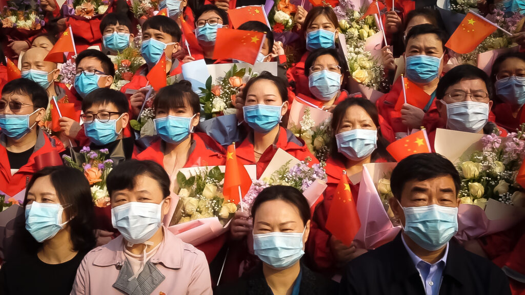 a crowd of people all in masks carrying flowers.