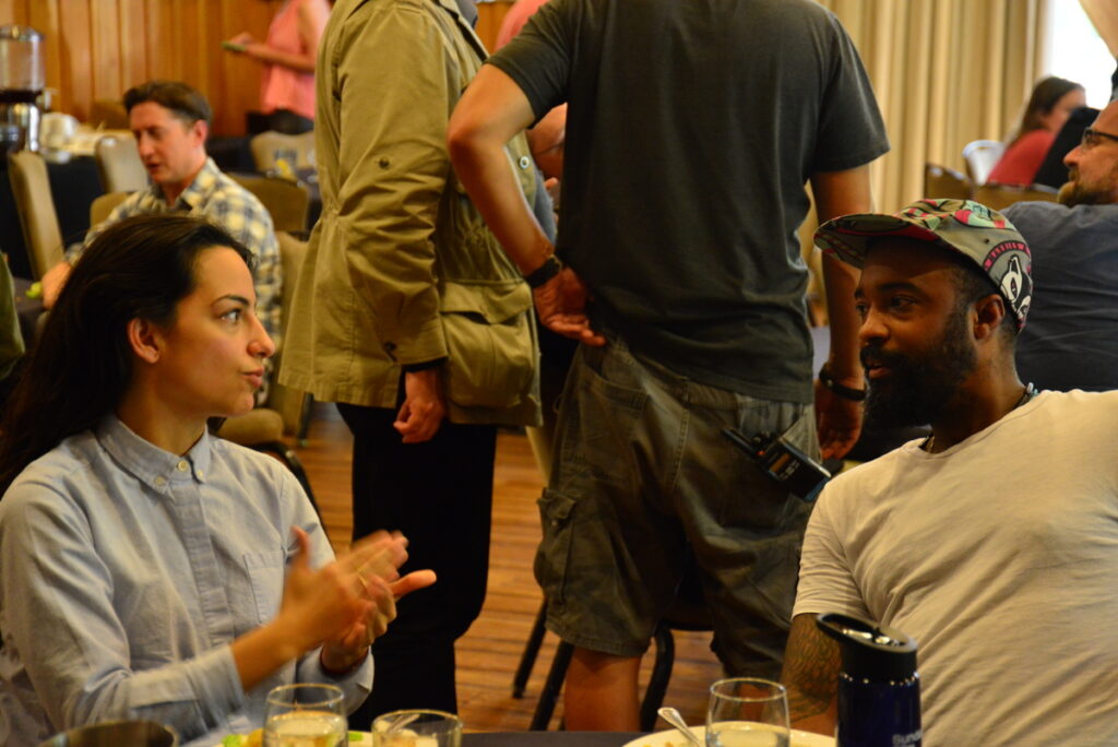 Woman and man in conversation around a table with food.