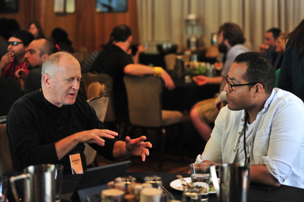 Two men in conversation around a table.