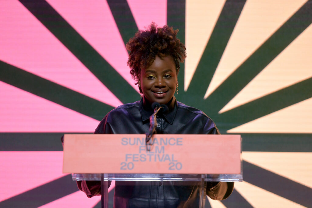Black woman, smiling, standing at a 2020 Sundance Film Festival podium