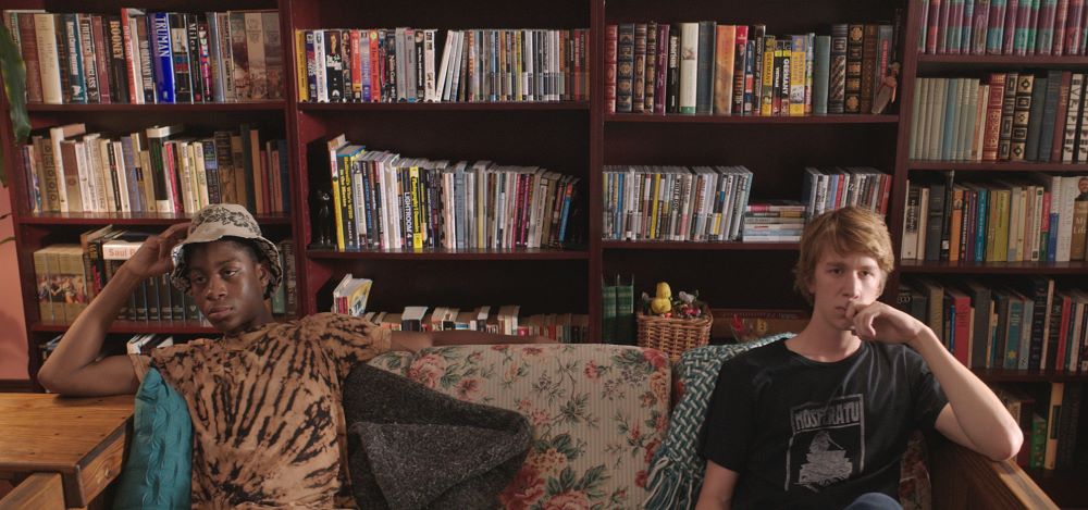 Two young men sitting in front of bookshelves