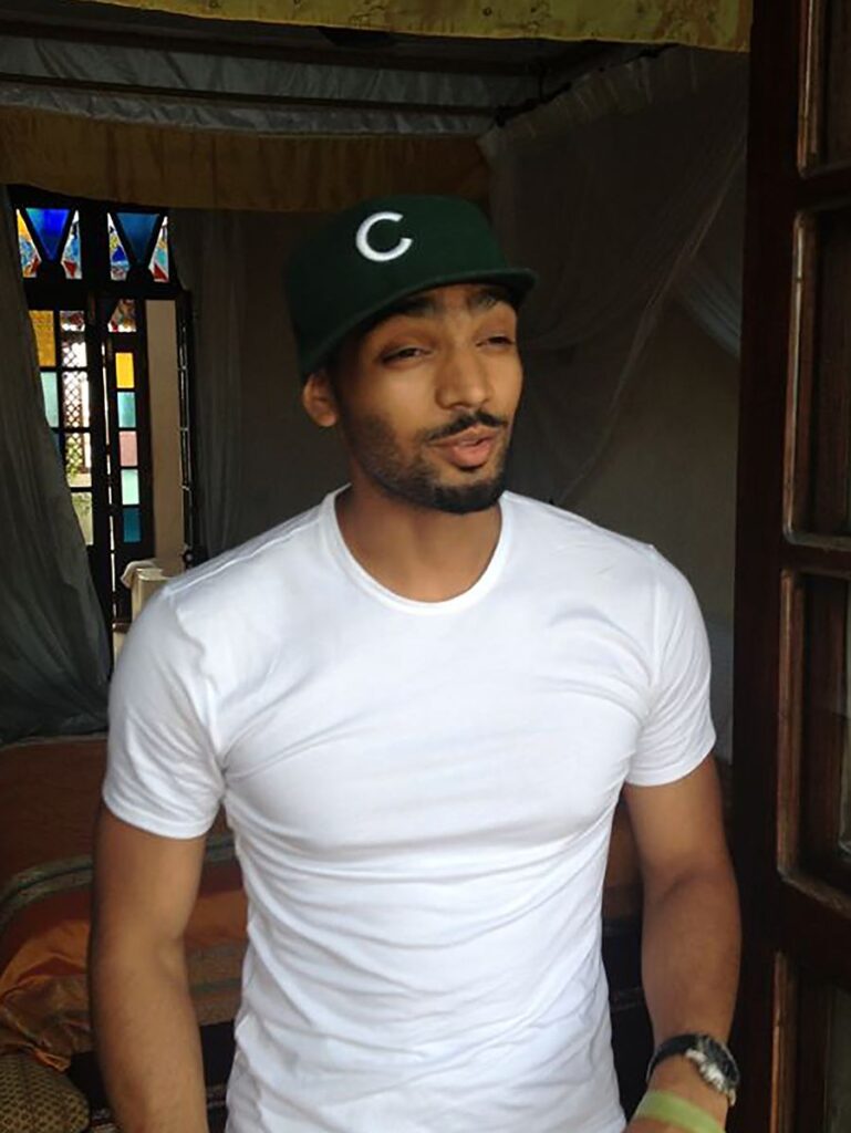 Man of color wearing a baseball cap and white T-shirt