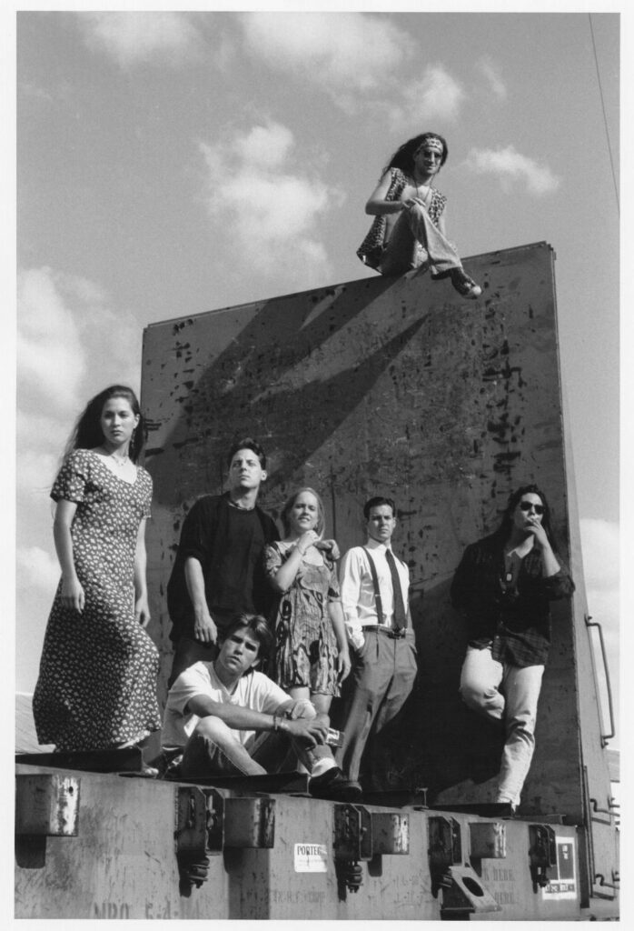 A group of young people stand on what appears to be a railroad car