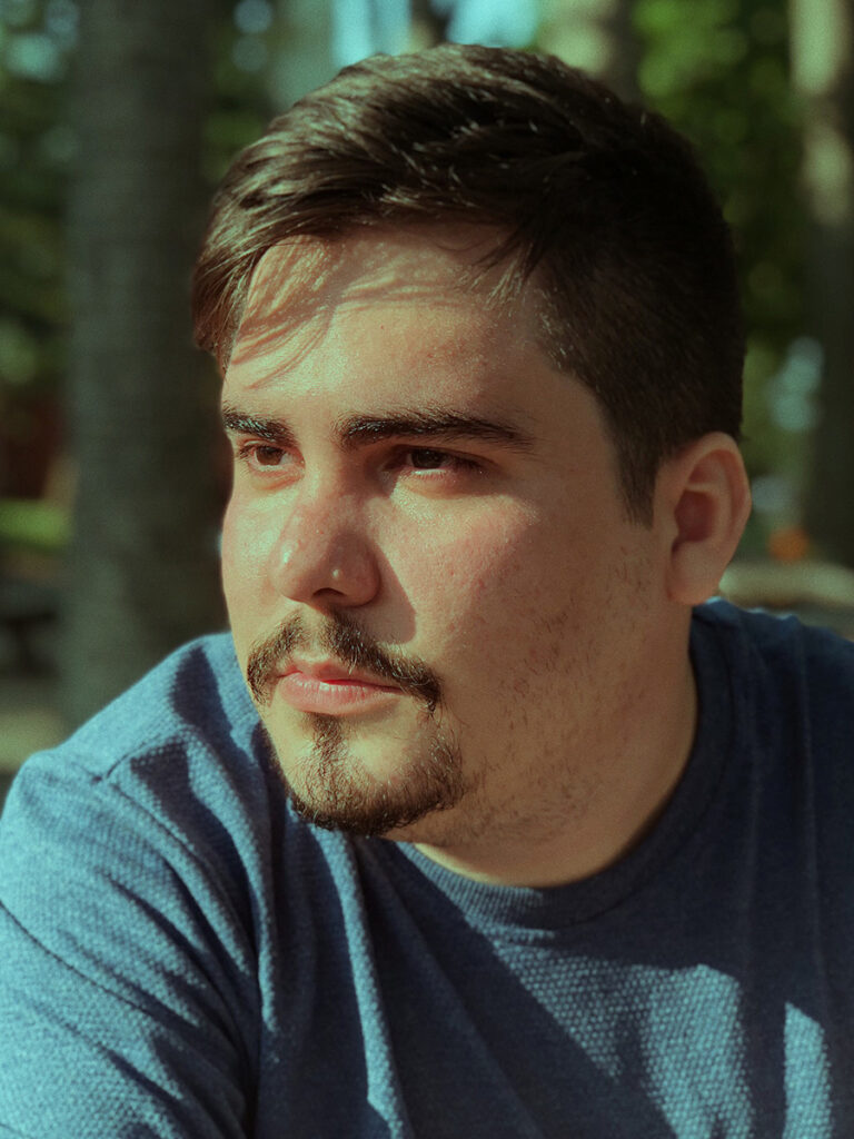 Man with mustache and goatee, wearing a blue T-shirt, looking to the side