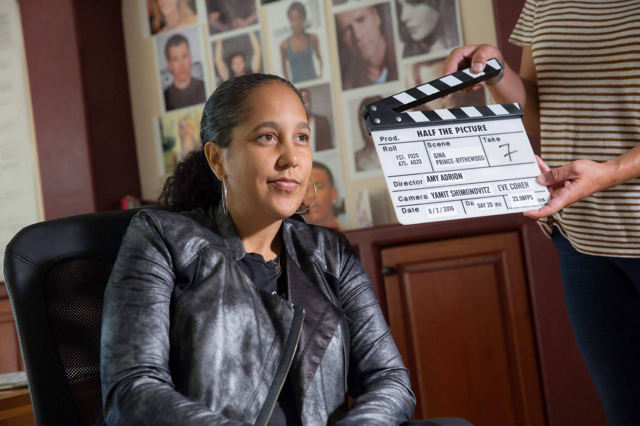 A Black woman looks at the camera as a director stands in front