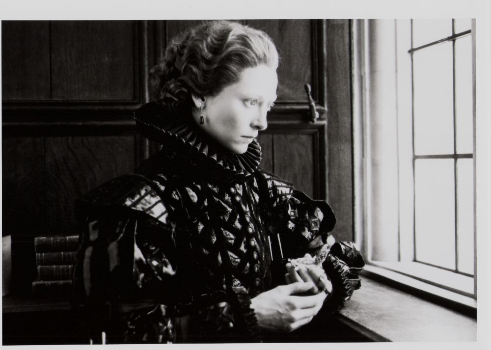 Person in Elizabethan attire stands before a window