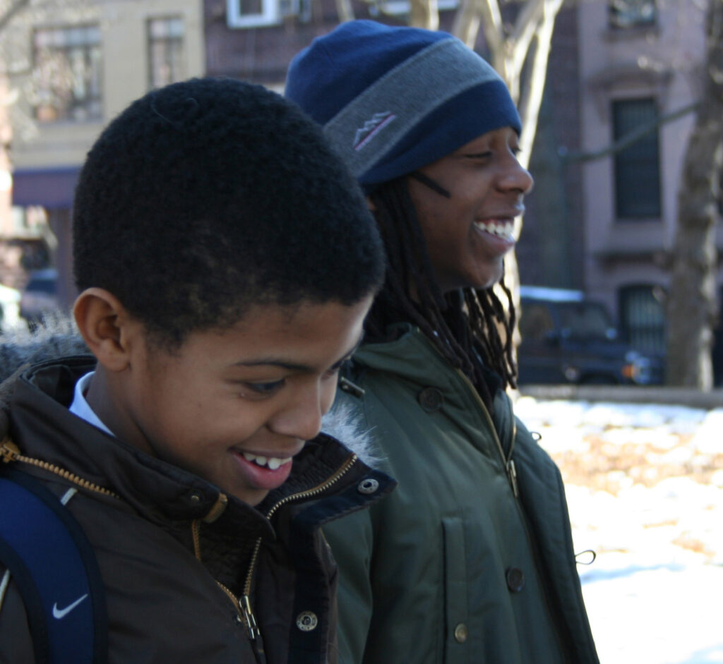 two Black boys smiling and looking to the right while wearing winter clothes