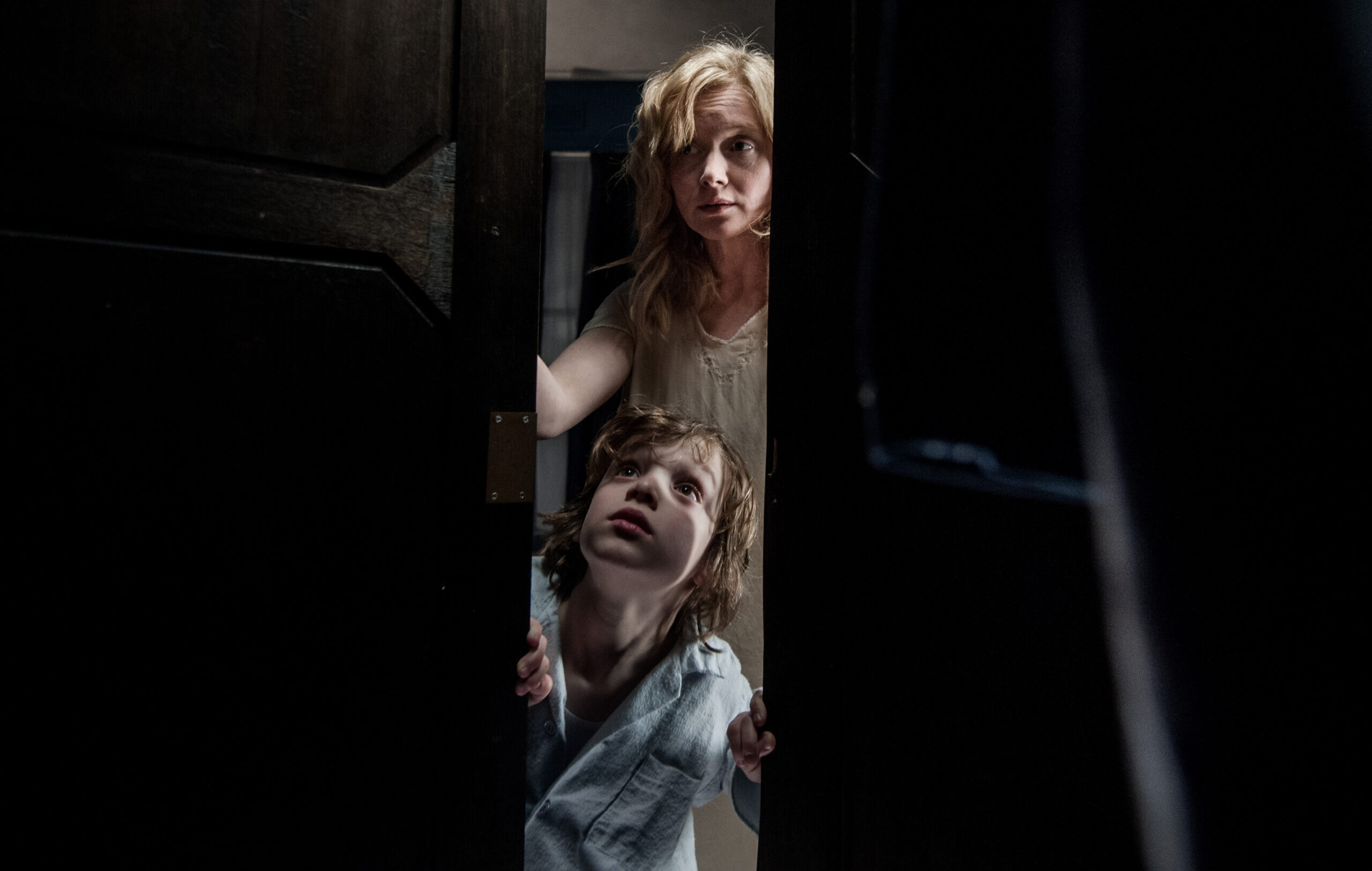 A mother and child looking through a closet door