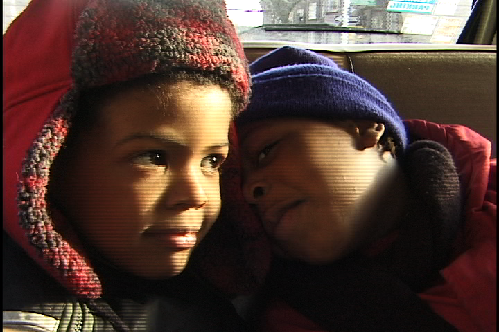 Two young black boys in the back of a car smiling