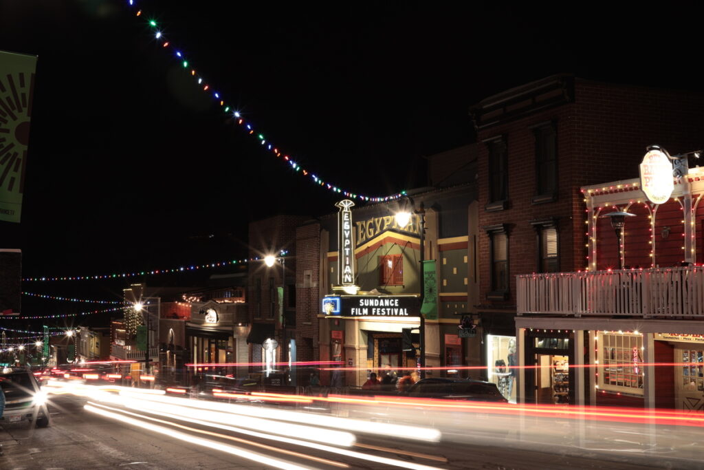 A busy highway in front of a theatre at night that says Sundance Film Festival