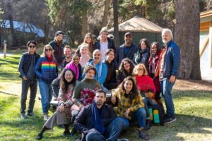 A group shot of all lab fellows, creative advisors, and program team smiling outside on the grass in the sunshine