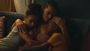 woman and two children hugging on a couch in a dim room