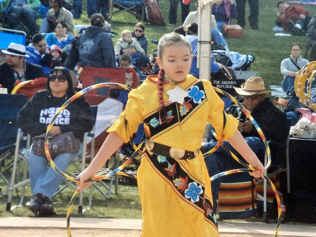 indigenous youth performing in a yellow ensemble