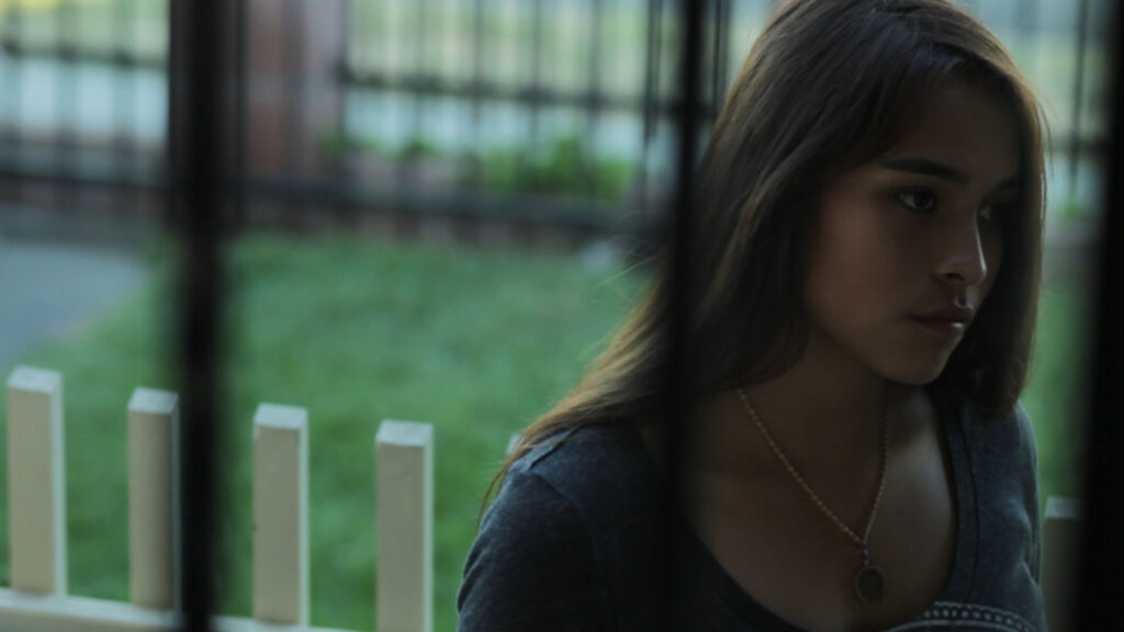 woman looking at a camera through a screen door