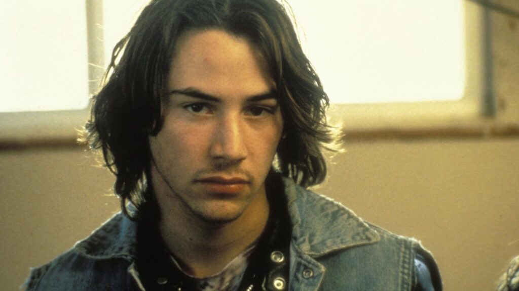 young man with shoulder length hair looking at the camera in a room