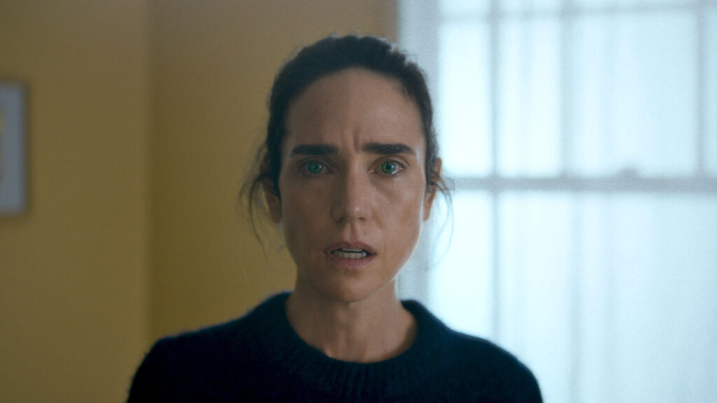 White woman with dark brown hair pulled back looks directly at camera