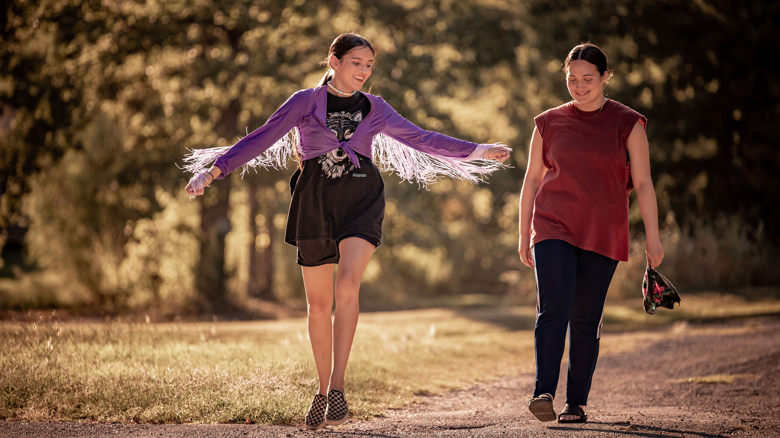 Two young indigenous women are walking on a street