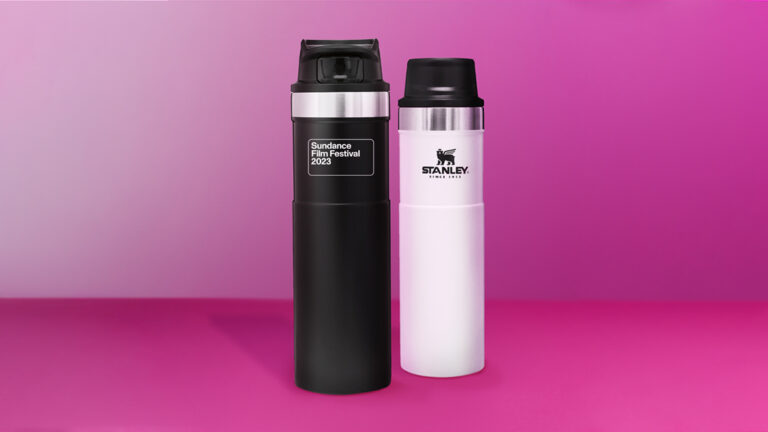 Two water bottles - one black and one white - standing in fron t of a pink backgound