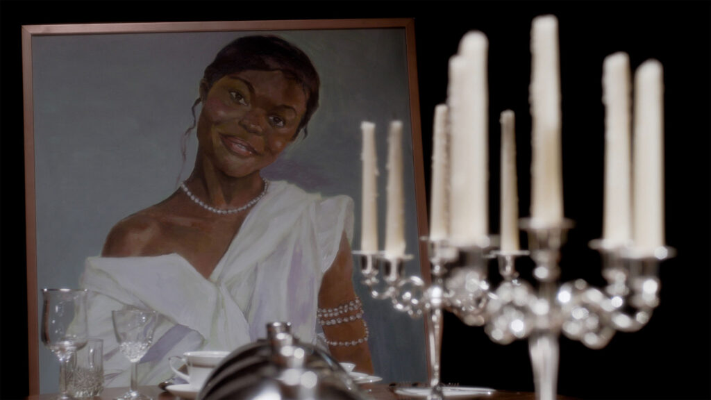 A painting of a young Black woman wearing a white dress and pearls. Candles are in front of the image.