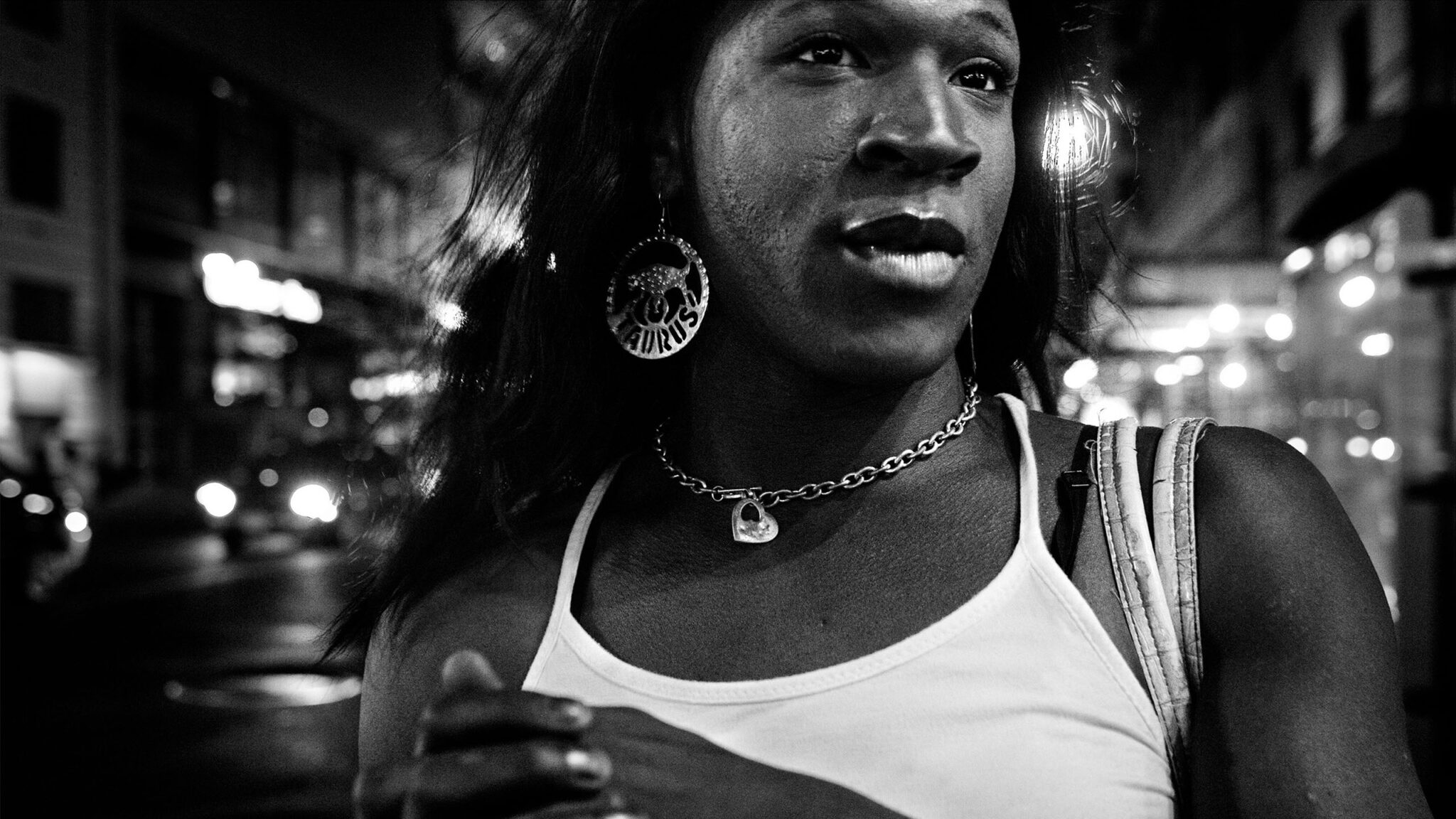 A black a white still of a Black woman wearing a white tank top looks off into the distance