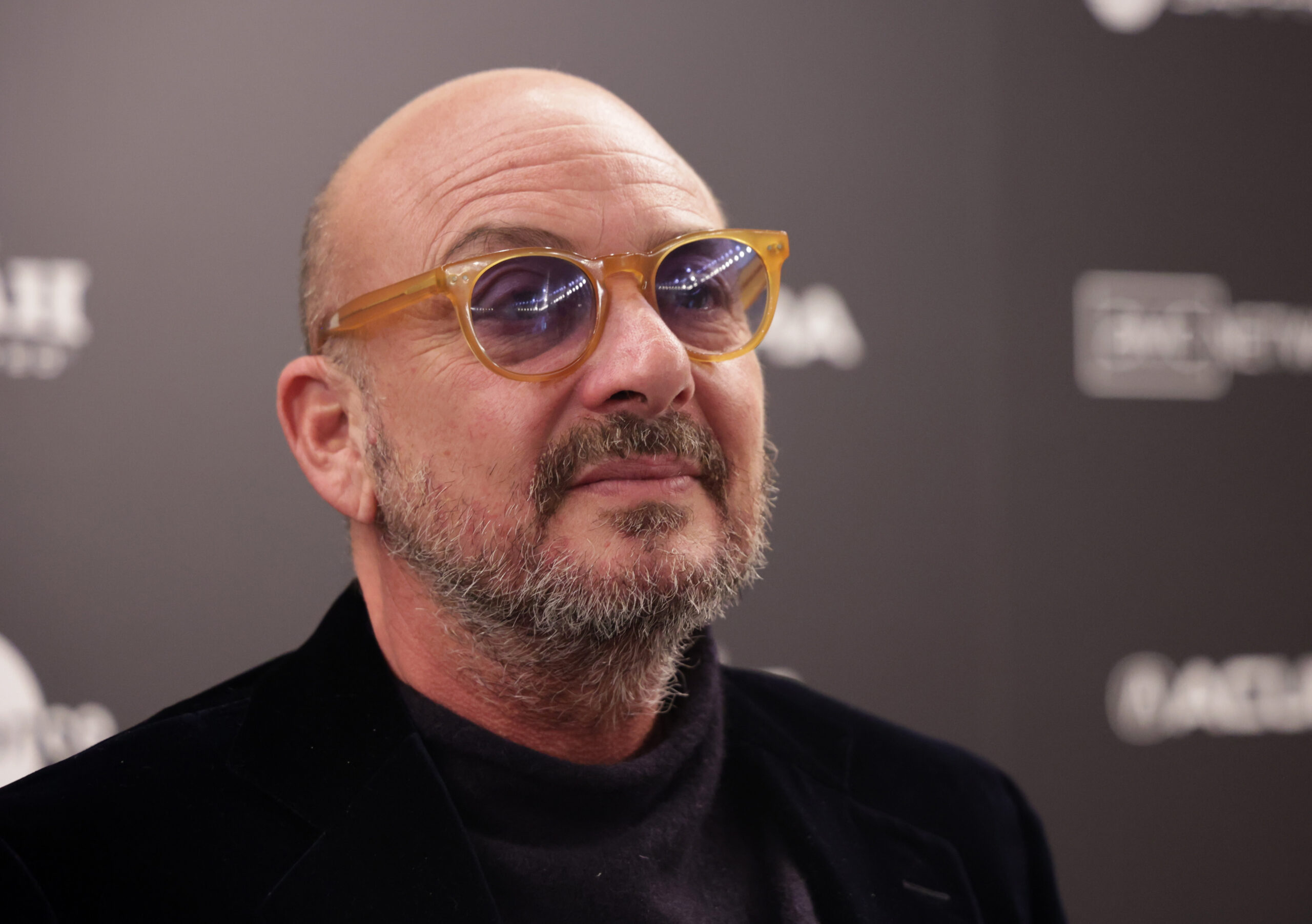 bald man with glasses smiling and looking towards the right