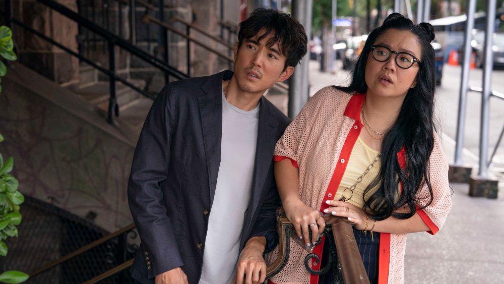 Young Asian man and woman standing side by side, looking to their right with puzzlement on their faces