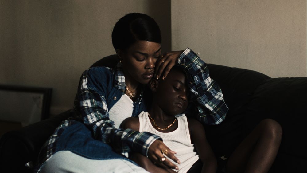 Black woman nestles a young Black boy in her arms.