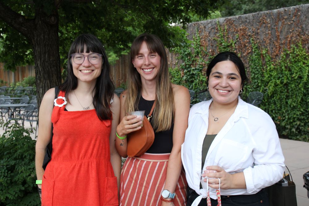 Three smiling women in a garden/patio setting