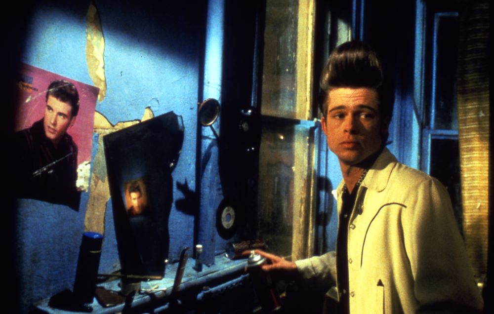 A young man with an extreme pompadour stands in front of a Ricky Nelson display.