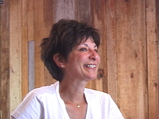 Head and shoulders shot of woman with short, dark hair smiling. Background is wood paneling.