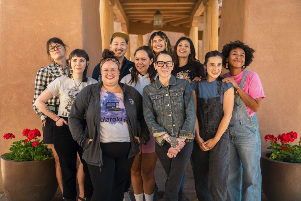 A group of advisors and fellows stand in front of a brown building in Santa Fe, New Mexico