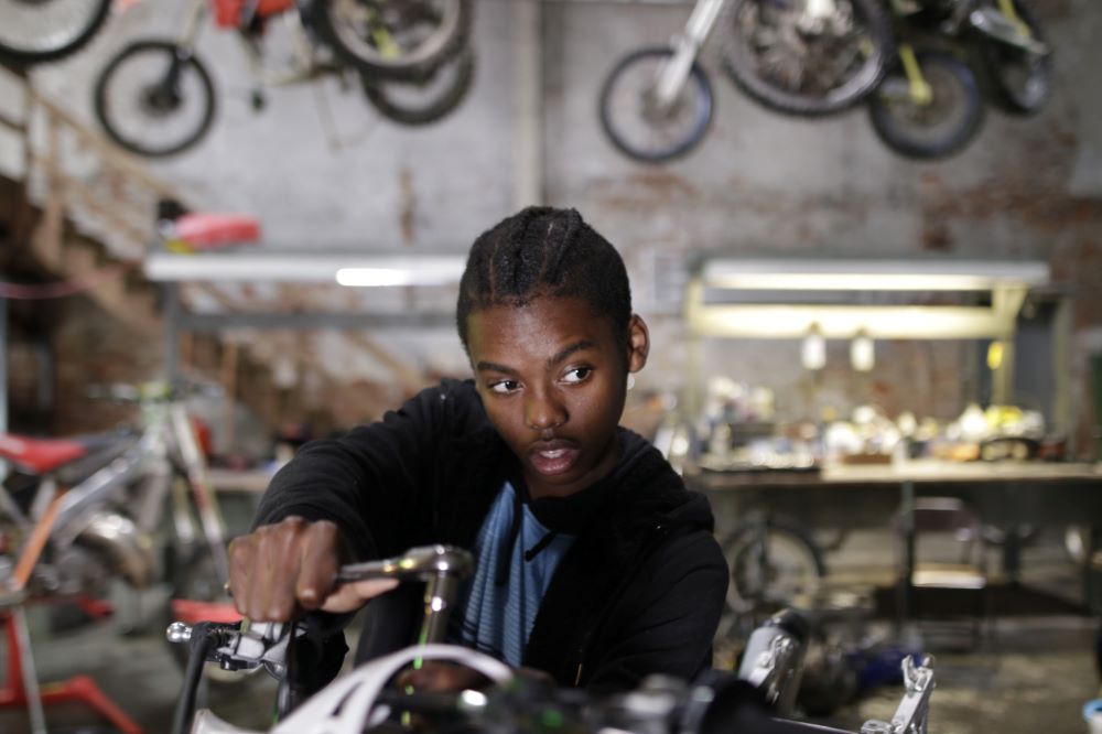 A young man appears to be working in a motorcycle repair shop