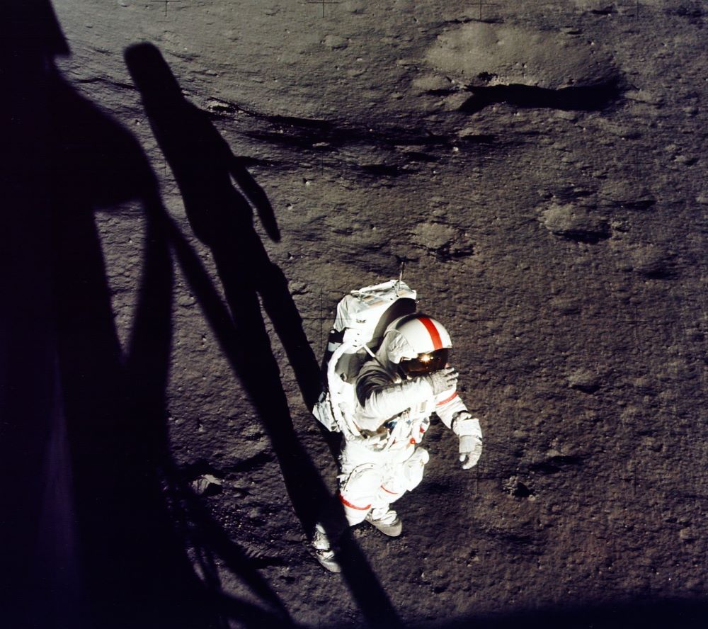 A person in a white spacesuit on what appears to be the moon's surface
