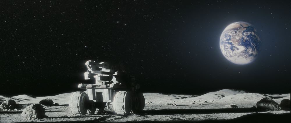 Some kind of vehicle traverses a moonscape (or other planetary landscape) and what appears to be Earth is in the background