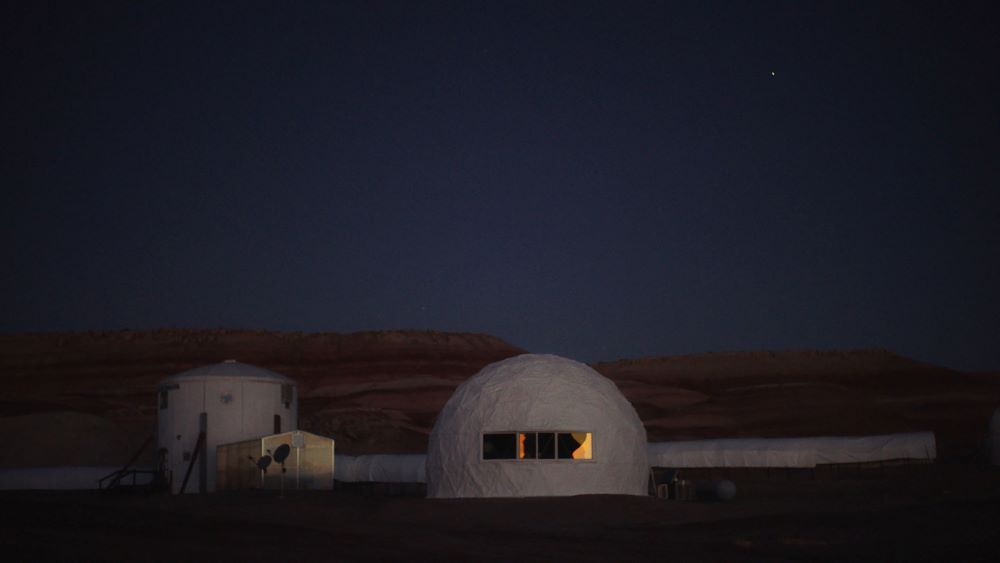 White dome-shaped building and other structures on what appears to be an alien landscape