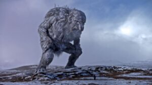 Giant troll looms over a tiny person on a frozen-looking landscape