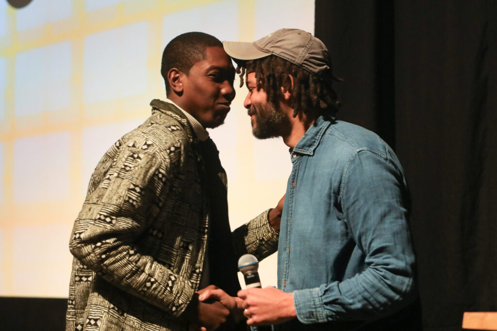 Kemba and J.M. Harper shake hands at the Library Center Theatre.