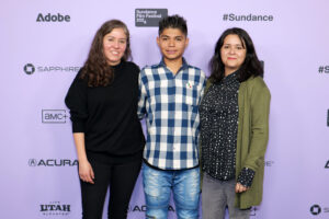 Fernanda Valadez, Juan Jesús Varela, and Astrid Rondero pose in front of a 2024 Sundance Film Festival backdrop.