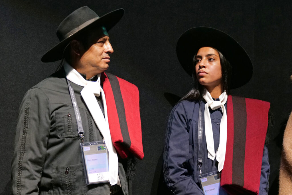 Dressed in traditional gaucho attire, Tati and Guadalupe Gonza stand in front of a black backdrop.