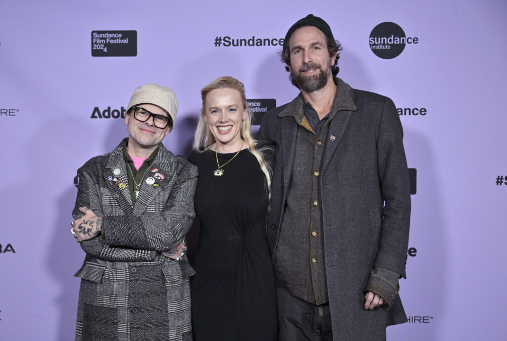 Two men and a woman stand in front of a Sundance Film Festival backdrop